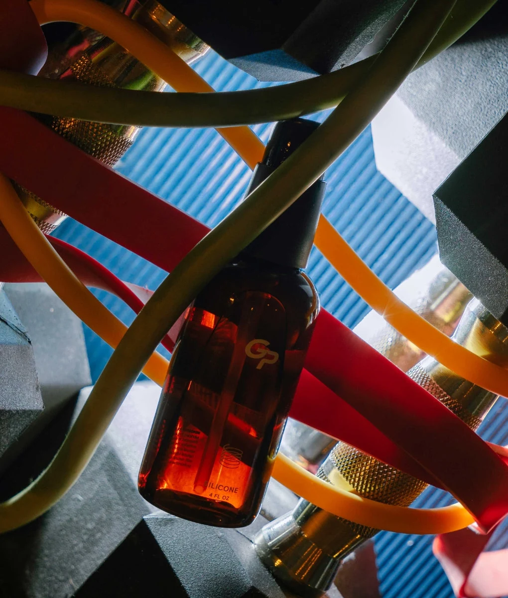 Goodparts silicone lubricant in an amber bottle among colorful chair slats