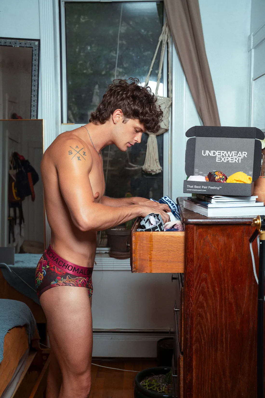 A man in patterned briefs choosing underwear from a drawer beside his Underwear Expert selection